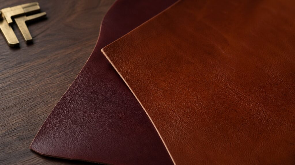 Composizione illustrativa di campioni di pelle pieno fiore color cognac e bordeaux con calibro su legno.