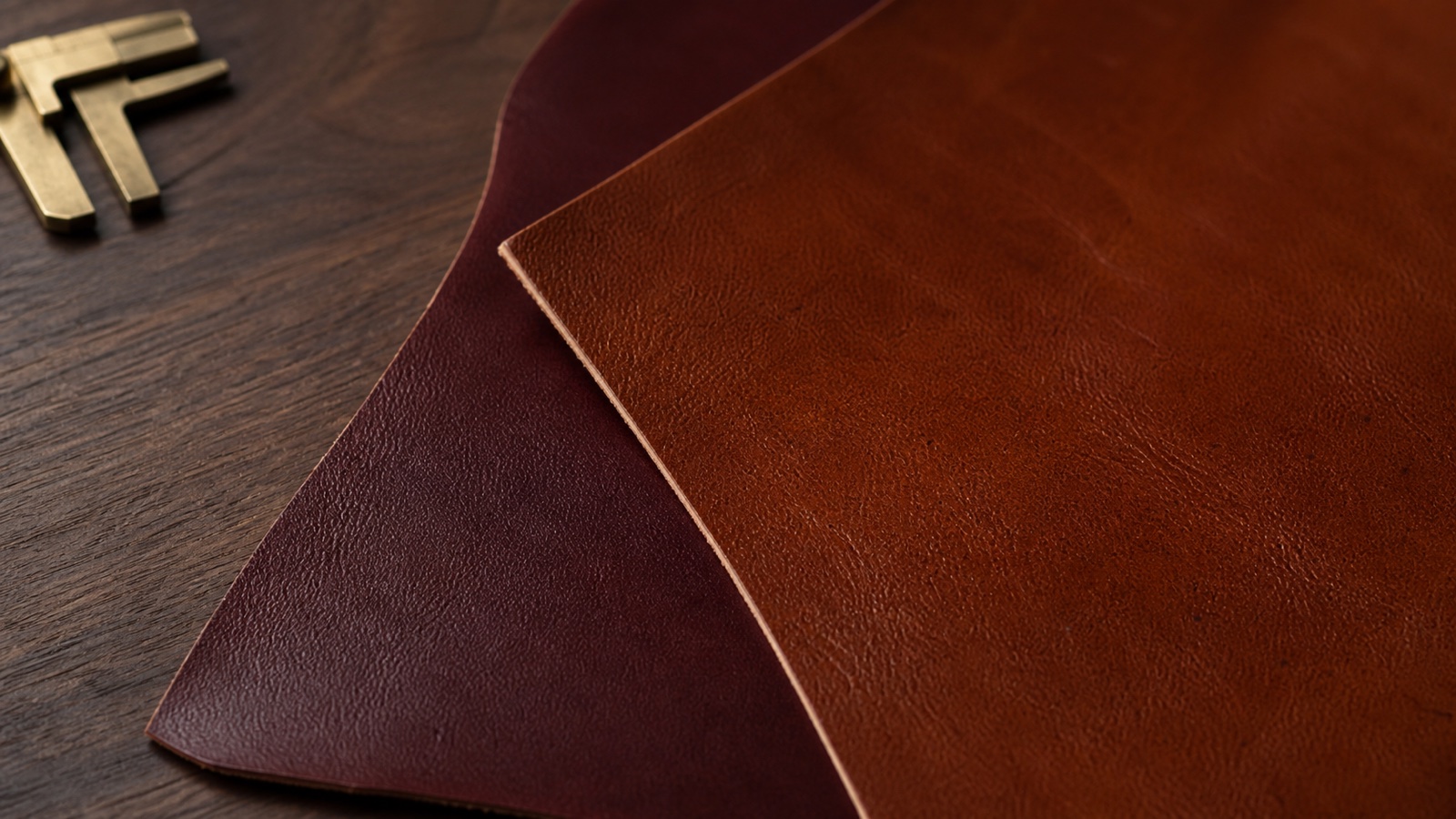 Composizione illustrativa di campioni di pelle pieno fiore color cognac e bordeaux con calibro su legno.